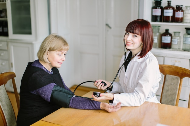 Médico tomando pressão arterial de paciente do sexo feminino no escritório