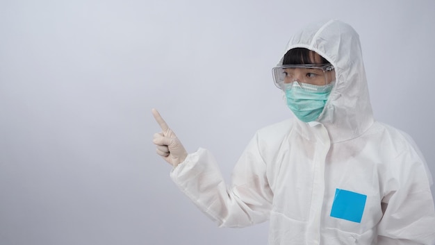 Médico con traje de PPE con guantes de goma médicos blancos y gafas transparentes y mascarilla verde N95 para proteger el gesto del coronavirus pandémico hacer el signo de la mano Representar la victoria sobre el virus Aislado