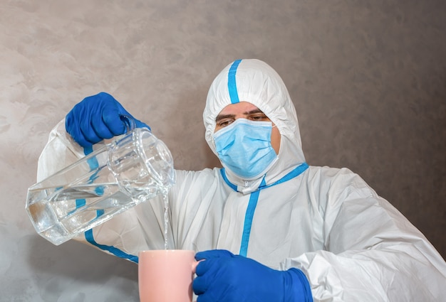 Médico con traje de protección médica, máscara y guantes que vierten agua para la prueba. Protección mers por epidemia de virus. Coronavirus (COVID-19). Concepto de salud.