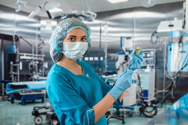 Médico con uniforme azul con guante protección completa contra virus con jeringa con medicamento