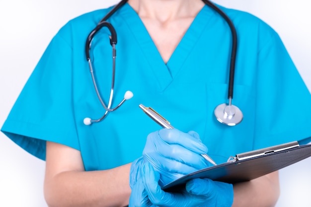 Un médico con uniforme azul y guantes está tomando notas.