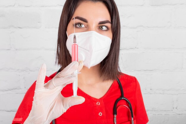 Un médico en uniforme con una jeringa.