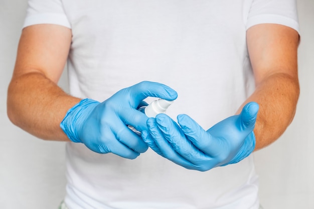 El médico usa un antiséptico con guantes azules.