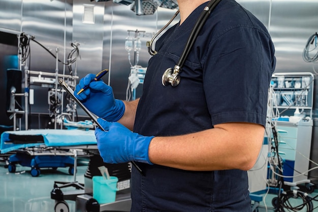 El médico usa uniforme y guantes, soporte para estetoscopio con portapapeles médico en la habitación del hospital