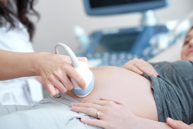 Médico usando equipamento de ultrassom para triagem de mulheres grávidas