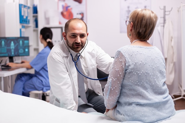 Médico usando estetoscópio durante a consulta com uma mulher idosa no hospital