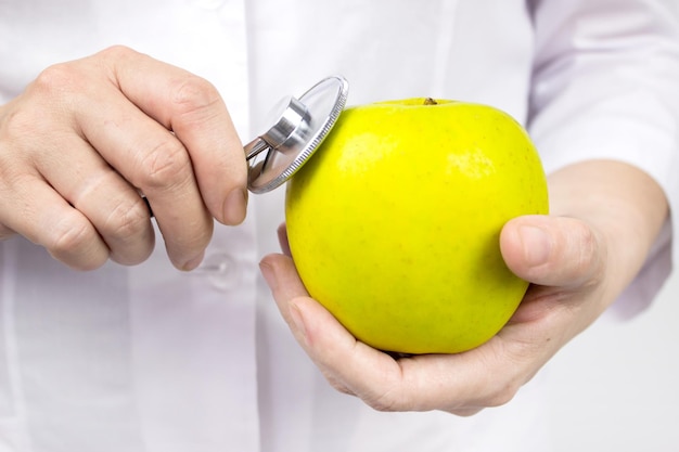 Médico usando estetoscópio para examinar uma maçã verde. bom conceito de nutrição de saúde médica. nutricionista com maçã, alimentação saudável.