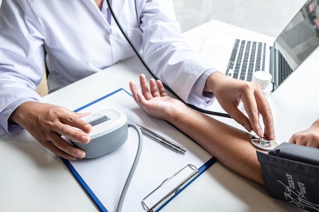 Foto médico usando estetoscópio verificando a medição da pressão arterial no braço de um paciente no hospital