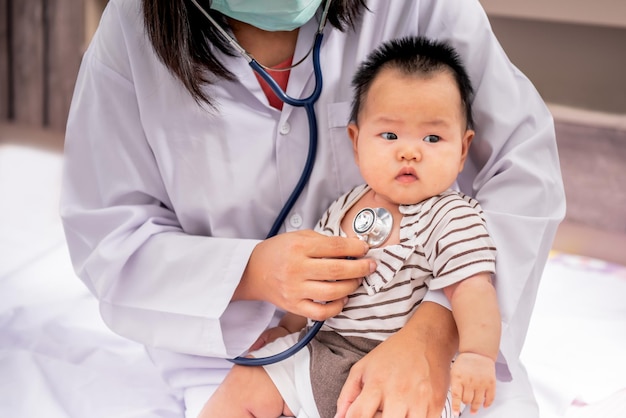 Foto médico usando estetoscópio verificando o sistema respiratório e os batimentos cardíacos de um bebê recém-nascido de 3 meses