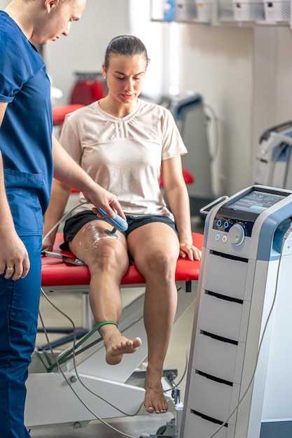 Foto médico usando una máquina para tratar las articulaciones de la rodilla de un paciente