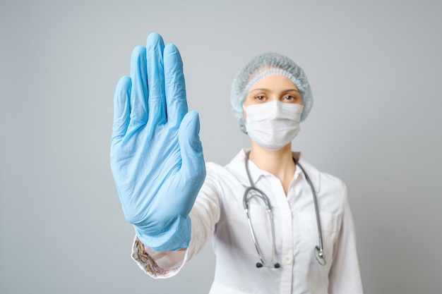 Médico usando máscara médica e luvas descartáveis, mostrando o gesto de parada
