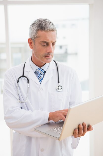 Médico usando o laptop sorrindo para a câmera