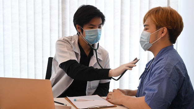 Médico usando paciente do sexo masculino de exame de estetoscópio na clínica