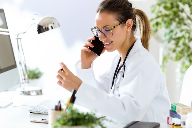 Médico usando su teléfono móvil en la oficina.