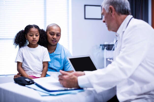 Médico usando tablet digital enquanto interage com o paciente