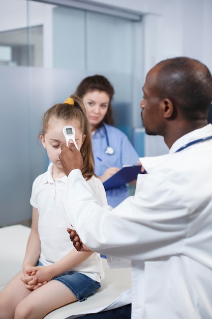 Foto médico usando um termômetro em menina