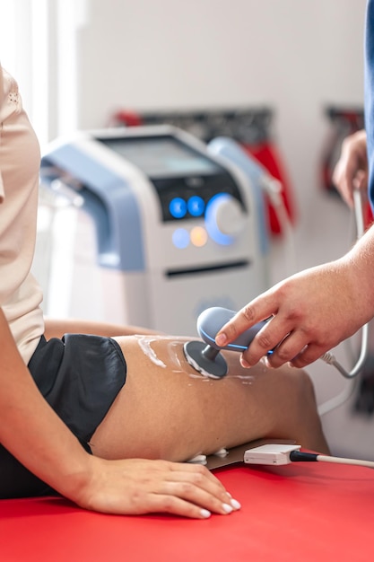 Médico usando uma máquina para tratar as articulações do joelho de um paciente