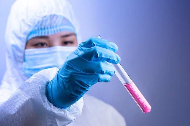 Médico usando uma máscara facial e luvas cirúrgicas, close-up de mão segurando a vacina covid.