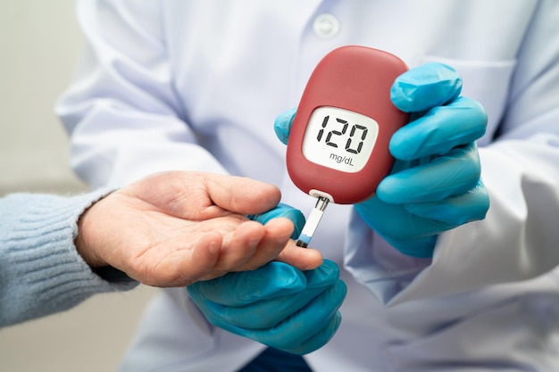 El médico utiliza un monitor de glucosa digital para medir y una tira de prueba para comprobar la diabetes a partir del nivel de azúcar en la sangre de los dedos