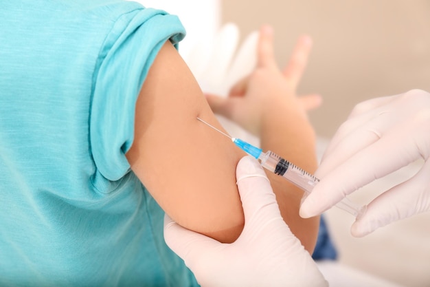 Médico vacinando criança pequena na clínica closeup