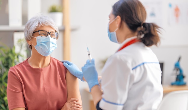 Médico vacinando uma mulher idosa Proteção contra vírus COVID2019