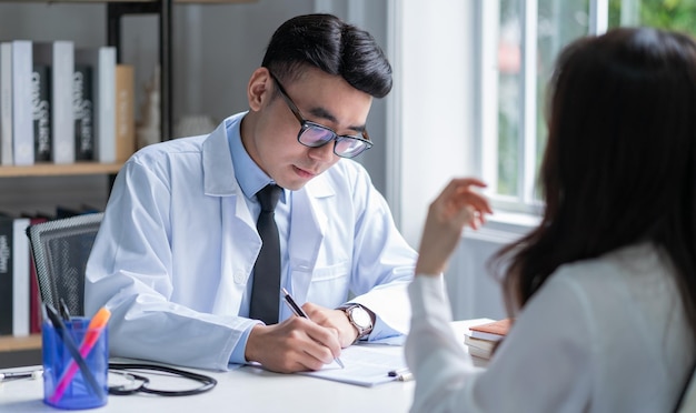 Médico varón asiático examinando al paciente en la clínica