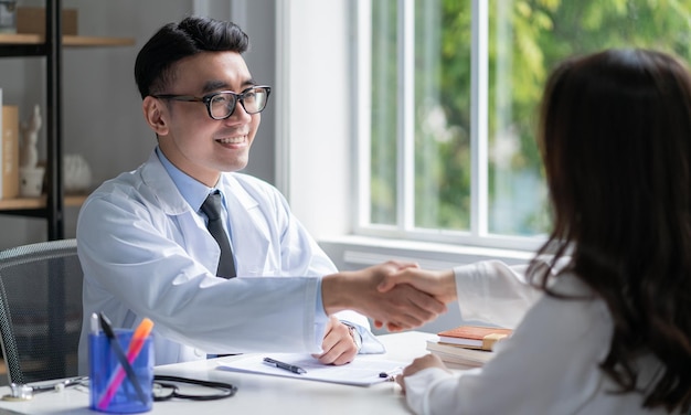 Médico varón asiático examinando al paciente en la clínica