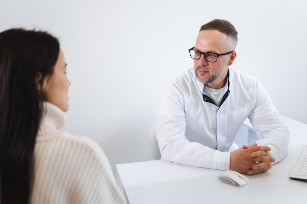 Médico varón hablando con una paciente en el consultorio