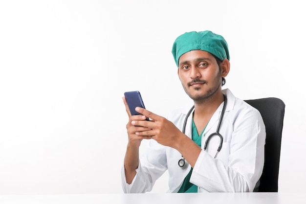 Médico varón indio joven que usa el teléfono inteligente en la clínica.