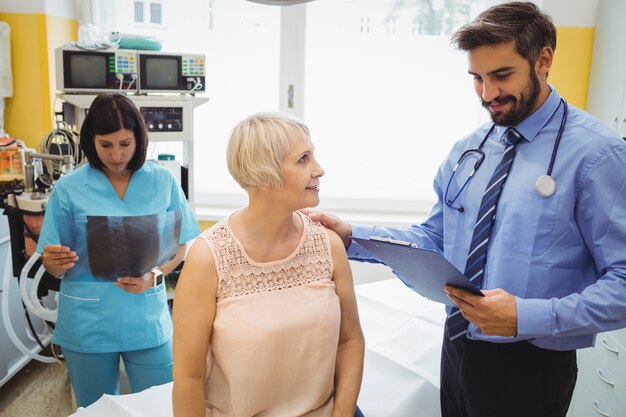 Foto médico varón interactuando con un paciente mientras la enfermera mirando rayos x