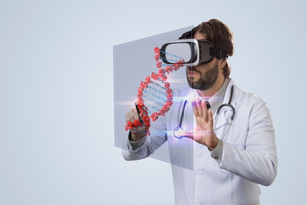 Médico varón sobre una pared gris, usando unas gafas de realidad virtual, mirando un ADN virtual