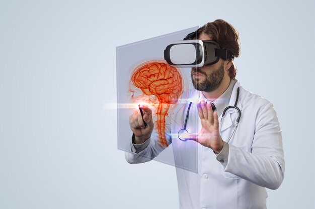 Médico varón sobre una pared gris, utilizando unas gafas de realidad virtual, mirando un cerebro virtual