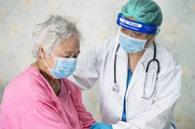 Médico verificando paciente asiática idosa ou idosa usando máscara facial no hospital para proteção contra infecção por covid-19 coronavirus.