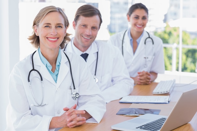 Médicos alegres posando em sua mesa