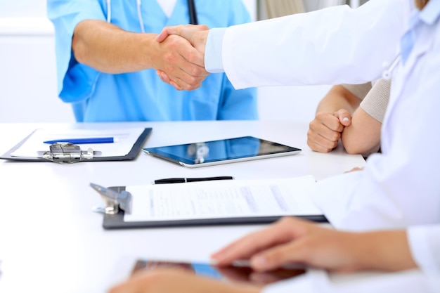 Médicos apertando as mãos uns aos outros terminando a reunião médica.