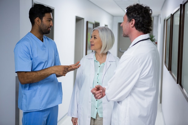 Foto médicos y cirujanos interactuando en corredor