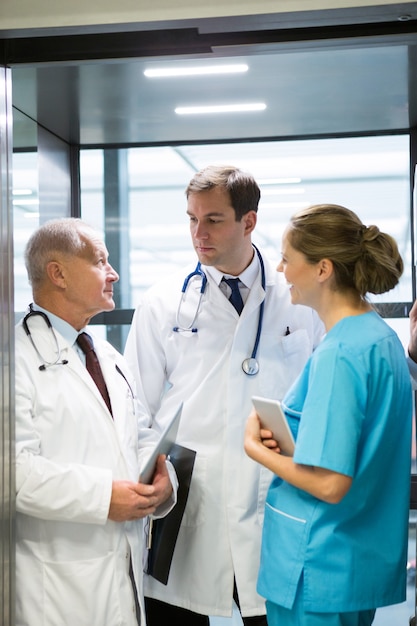 Médicos y cirujanos interactuando entre sí en ascensor.