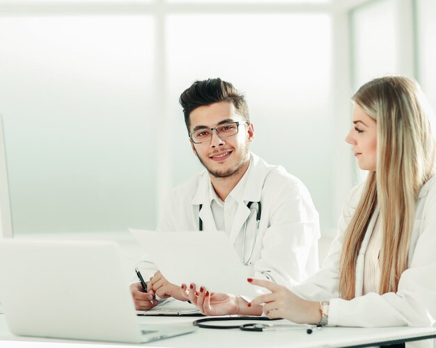 Los médicos colegas sentados en una mesa en la oficina