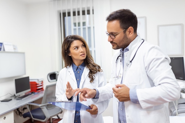 Foto médicos confiados discutiendo sobre la ficha médica trabajadores de la salud masculinos y femeninos llevan abrigos de laboratorio están trabajando en el hospital