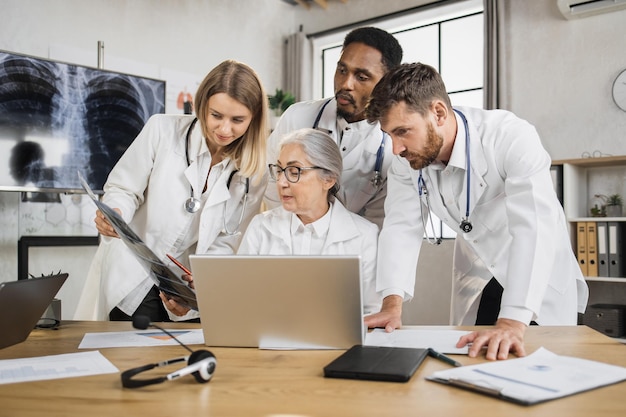 Médicos discutiendo la exploración de rayos X con el médico principal en la clínica