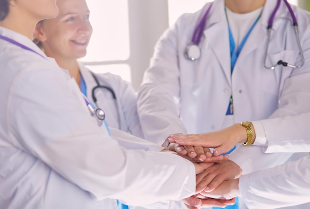 Médicos e enfermeiros empilhando as mãos isoladas em branco