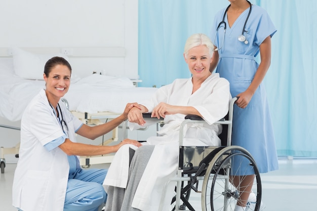 Médicos e paciente em cadeira de rodas