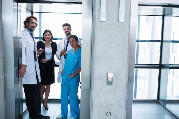 Médicos y empresaria de pie en el elevador