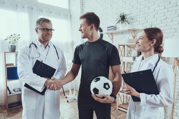 Los médicos están hablando con el jugador de fútbol.