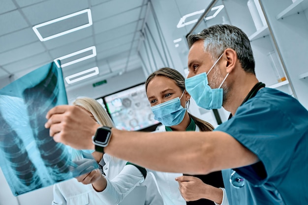 Médicos masculinos e femininos consultando em escritório brilhante discutindo imagem de raio x vista lateral foco seletivo