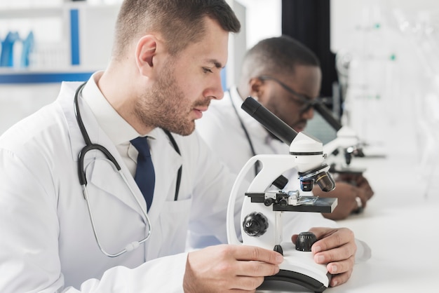 Médicos con microscopios en el laboratorio