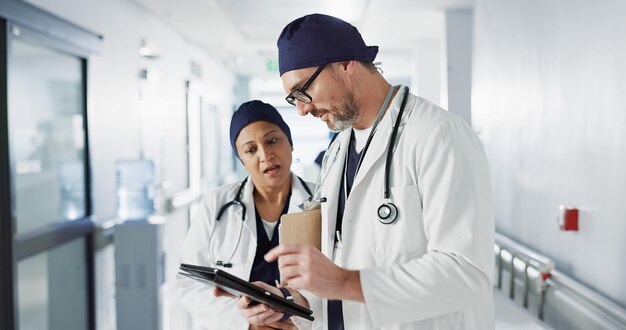 Médicos, personas y trabajo en equipo en tableta para asesoramiento en atención médica, planificación de horarios y gestión de clínicas. Cirujana médica y mentora con soporte, actualización del hospital y conversación sobre resultados digitales.