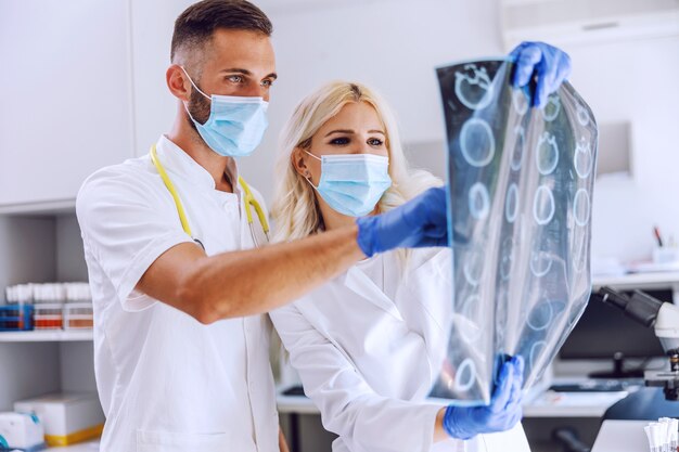 Médicos de pie en el hospital y mirando la radiografía del cerebro del paciente.