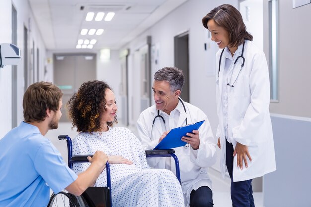 Médicos que interactúan con una mujer embarazada en el corredor