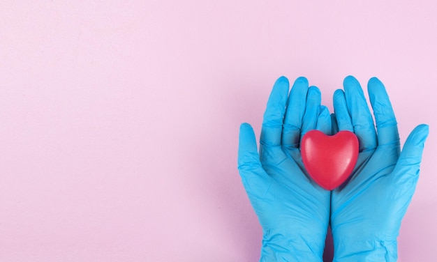Los médicos tienen las manos en guantes médicos en forma de corazón sobre fondo azul.